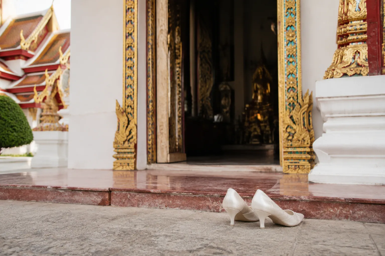Wedding footwear arranged for removal before entering a Thai temple area