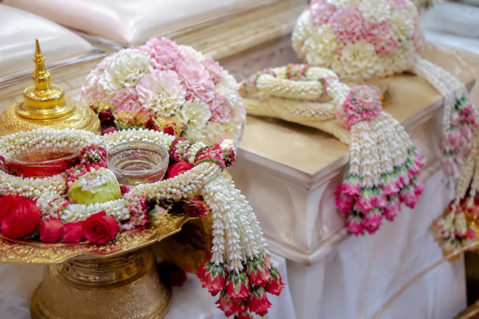 Floral tray and fresh garland details near a Thai wedding water-pouring ceremony table